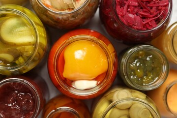 Many jars with different preserved products on white table, flat lay