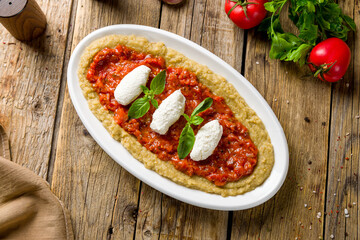 babaganoush dish on wooden table, eggplant paste with cheese and tomato paste on wooden table top view