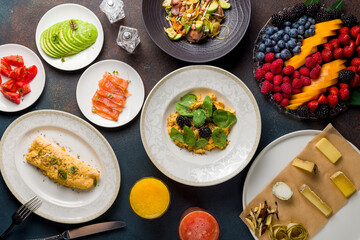 scramble with spinach and truffle, avocado, salmon, omelete, berries plate, cheese plate, asian salad with beef on stone table top view