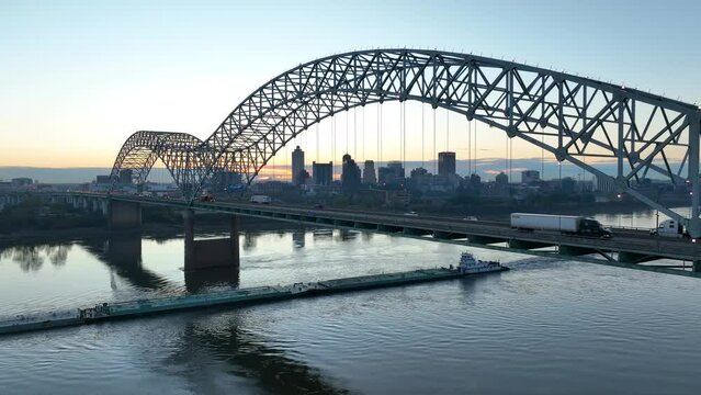Memphis Tennessee skyline framed in Hernando de Soto bridge. Barge on Mississippi River. Aerial establishing shot.