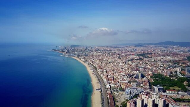 Barcelona Catalunya beach aerial shot of the sea the train the city during a sunny day without clouds and a spectacular background with the mountains and surroundings