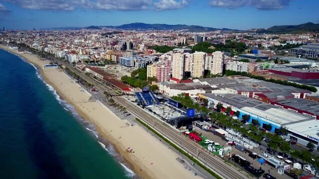Barcelona Badalona  Catalunya beach aerial shot of the sea the train the city during a sunny day without clouds and a spectacular background with the mountains the industrial sites and surroundings