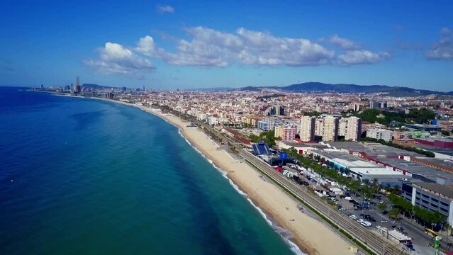 Badalona Barcelona Catalunya beach aerial shot of the sea the train the city during a sunny day without clouds and a spectacular background with the mountains the industrial sites and surroundings