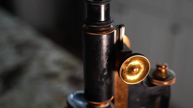 Blurred then push in to reveal an antique microscope with shiny brass knobs - macro