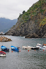 Fototapeta na wymiar Small boats lie idle in a harbor along the Italian coast of Cinque Terre. 