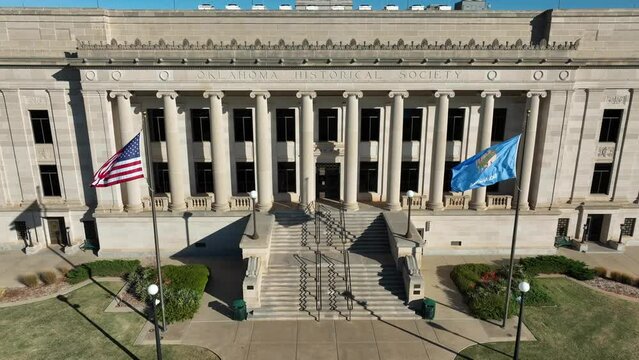 USA and OK state flag at Oklahoma Historical Society building. Aerial pullback reveal.