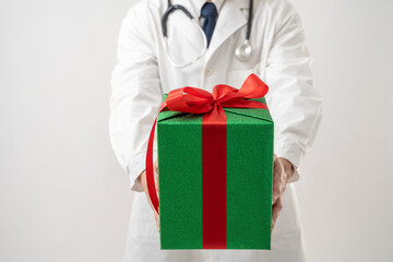 Portrait of Asian Doctor in glasses with stethoscope carrying gift box isolated on white background