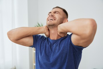 Man back neck and shoulder pain, inflammation of muscles and ligaments rupture during sports, inflammation and injury, in a blue t-shirt at home