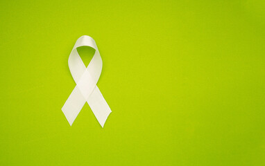 A white ribbon symbol the fight against lung cancer on a green background