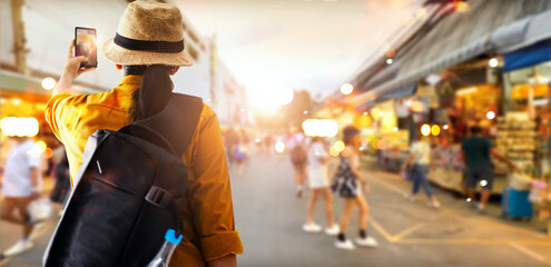 Female tourist traveling backpacker happy and take a photo in outdoor night  market.