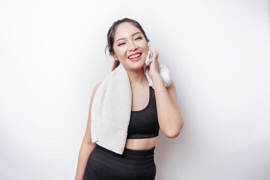 Sportive Asian woman posing with a towel on her shoulder, tired after workout