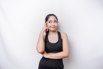 Thoughtful sporty Asian woman wearing sportswear is looking aside while touching her chin, isolated by white background.