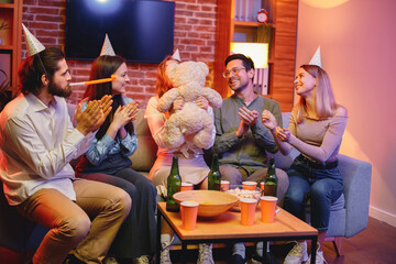 Friends sitting on a sofa in a cozy room and celebrating birthday