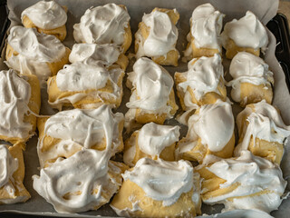 Close-up of cookies with white cream lying on an iron baking sheet lined with parchment paper. Top view of cookies with white cream on a baking sheet ready for baking. Step by step cookie recipe