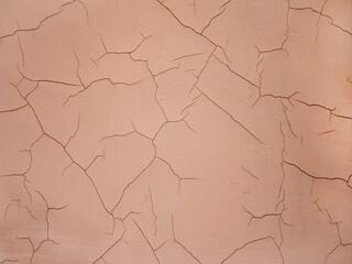 Close-up cracks on an old concrete wall. The wall is painted with beige paint with beautiful cracks. The concept of renovation of old buildings.