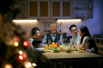 three generation asian family having christmas dinner together at home