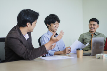 Cheerful young business people having discussion on meeting at the office.