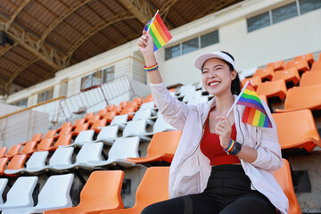 Happy and excited young female asian transgender LGBT sport fan cheering and watching the match...