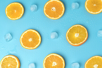 Juicy oranges on a background of ice cubes with copy space on a blue background
