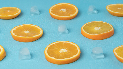 Fototapeta premium Juicy oranges on a background of ice cubes with copy space on a blue background