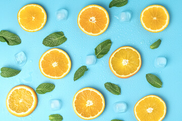 Fototapeta na wymiar Juicy oranges with ice cubes and mint leaves with copy space on blue background