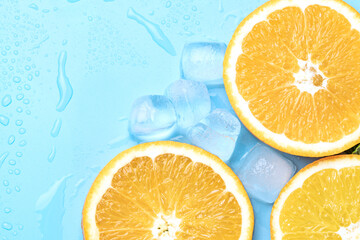 Juicy oranges on a background of ice cubes with copy space on a blue background