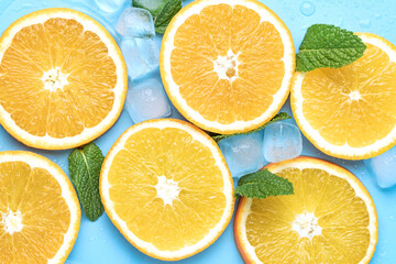 Juicy oranges with ice cubes and mint leaves with copy space on blue background