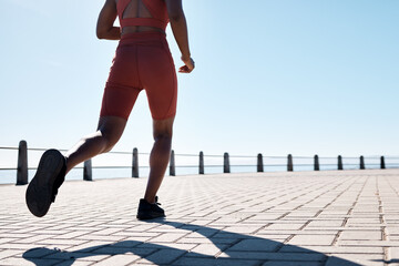 Running, legs and promenade with a sports woman or runner outdoor for an exercise with blue sky mockup. Fitness, workout and shoes with a female athlete taking a run for cardio or endurance training