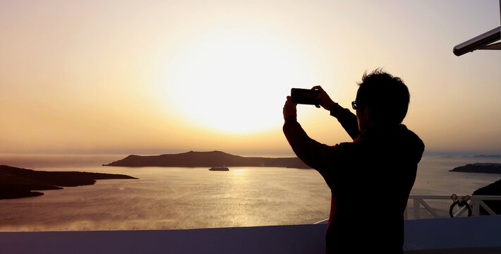 Happy moment with sunset sky scene with nomad digital man using smartphone take a picture at Santorini island,Greece