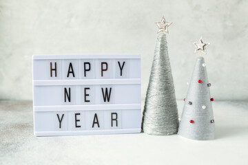 Lightbox with text HAPPY NEW YEAR with yarn wrapped XMAS cone trees. New year celebration. Happy New Year concepts