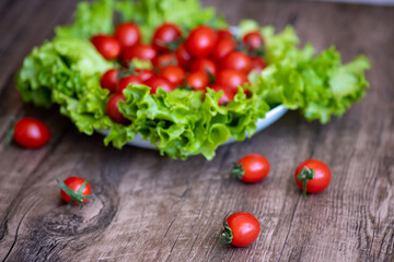 fresh, ripe tomatoes and lettuce ona plate on wooden background