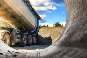 A large dump truck unloads rubble or gravel at a construction site. Car tonar for transportation of...