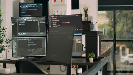 Computer screens on desk running programming code data algorithms in empty coding room. Database...