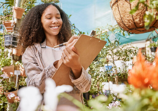 Small business, plants and black woman with inventory, quality control and checklist clipboard in nursery. Smile of satisfied business owner writing quality assurance notes in flower garden.