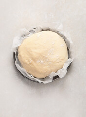 Raw dough pastry in a bowl on neutral background.