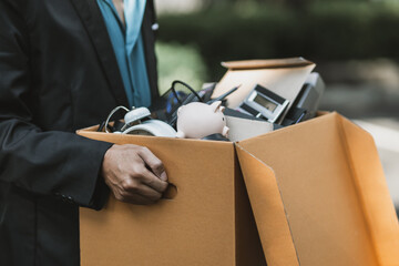 Businessman fired or resign from the company are carrying boxes down the street looking for a new job. Unemployed, hiring job, quitting job concept..