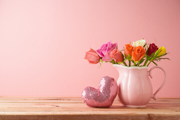 Happy Valentine's day concept. Rose flower bouquet and heart shape on wooden table over pink...