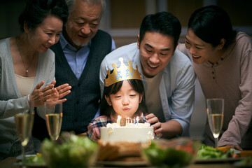 three generation asian family celebrating little girl's birthday at home