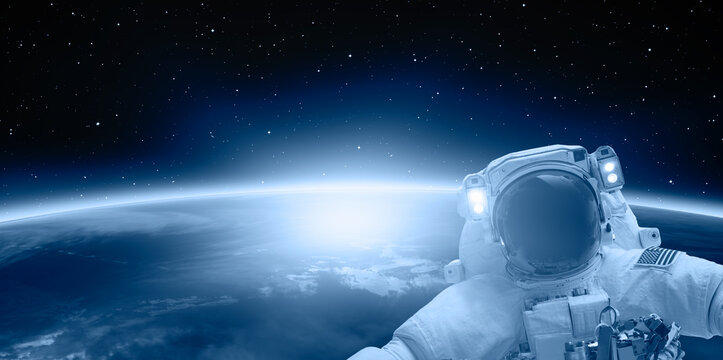 An astronaut doing a spacewalk - Planet Earth with a spectacular sunset "Elements of this image furnished by NASA"