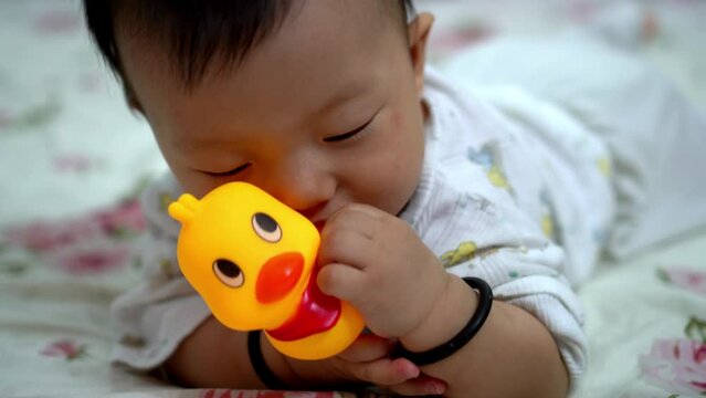 Little kid hold the rubber duck while lay at bed