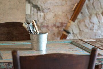 Cutlery set inside a metal bucket in a retro restaurant. © sinseeho