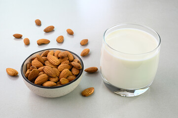 Almond milk in a glass cup with almonds in a bowl