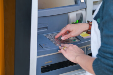 Close up of hands of a person using ATM keyboard