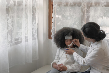 Young black american mother feeding rices porridge to her sick daughter with unhappy face due to a...