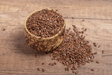 flax seeds in a wooden bowl on a wooden background, top view