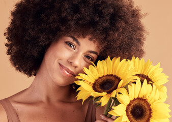 Skincare, natural and black woman portrait with sunflower bouquet for afro hair care, beauty and cosmetic campaign. Smile of beautiful model with healthy skin and hair texture in beige studio.