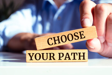 Closeup on businessman holding a wooden blocks with text CHOOSE YOUR PATH, business concept