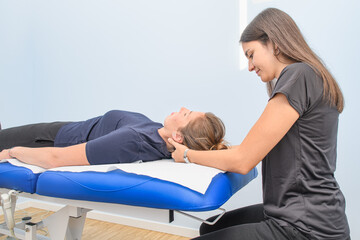 A physical therapist treats a patient's neck and cervical - 554799490