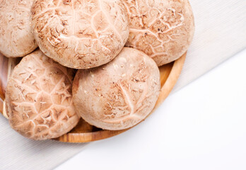 Shiitake mushrooms in a wooden bowl close-up top view.