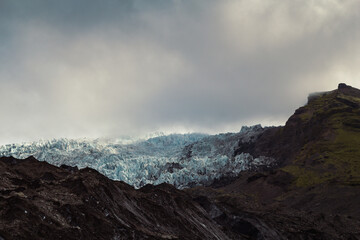 Rocky mountain ridge with ice landscape photo. Beautiful nature scenery photography with gloomy sky on background. Idyllic scene. High quality picture for wallpaper, travel blog, magazine, article